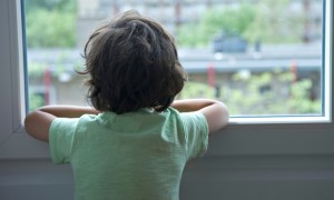Lonely little boy looking out of the window